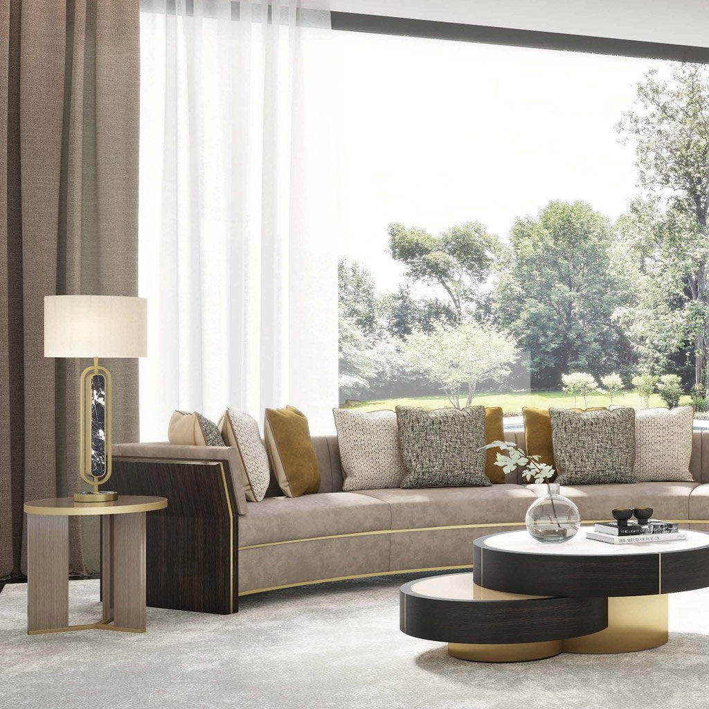 Lifestyle image of luxury small round three legged accent table with brass detail. Shown in luxurious living room with a wide sofa and spectacular view.