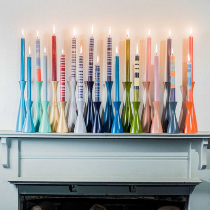 A lifestyle image of the tall candle collection in candle holders, placed on a fireplace mantle