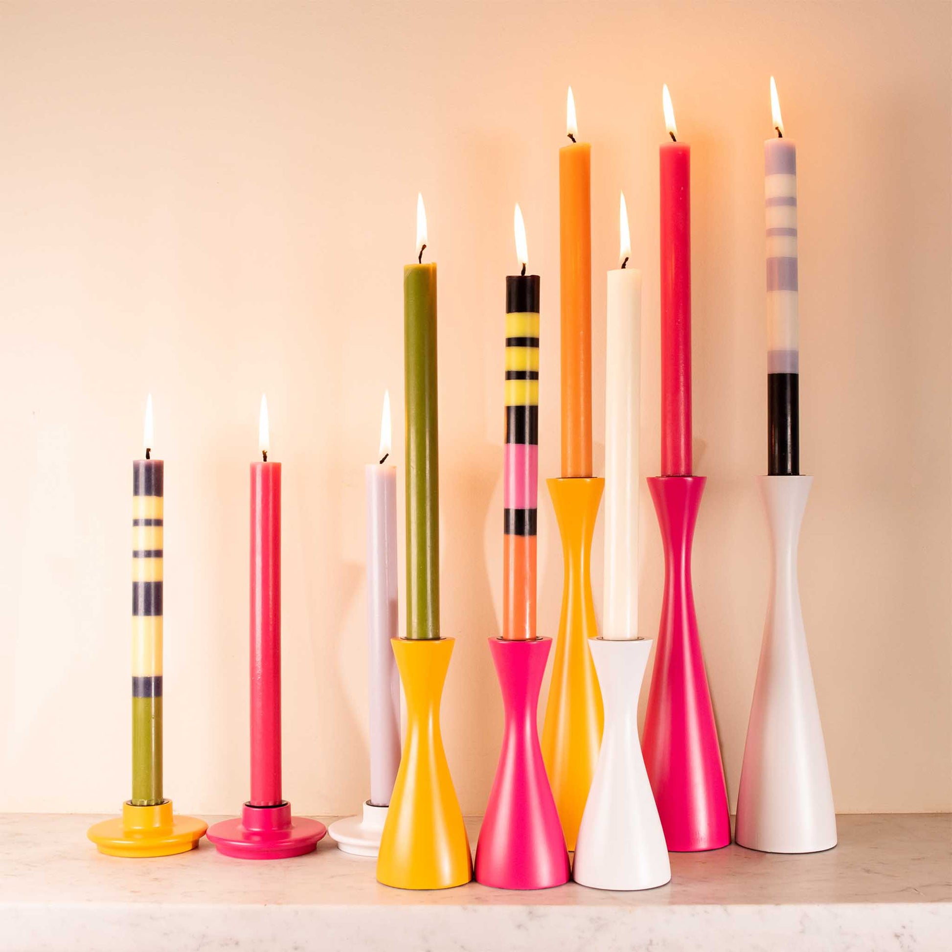 an image showing lit striped candles from the collection in matching candle holders