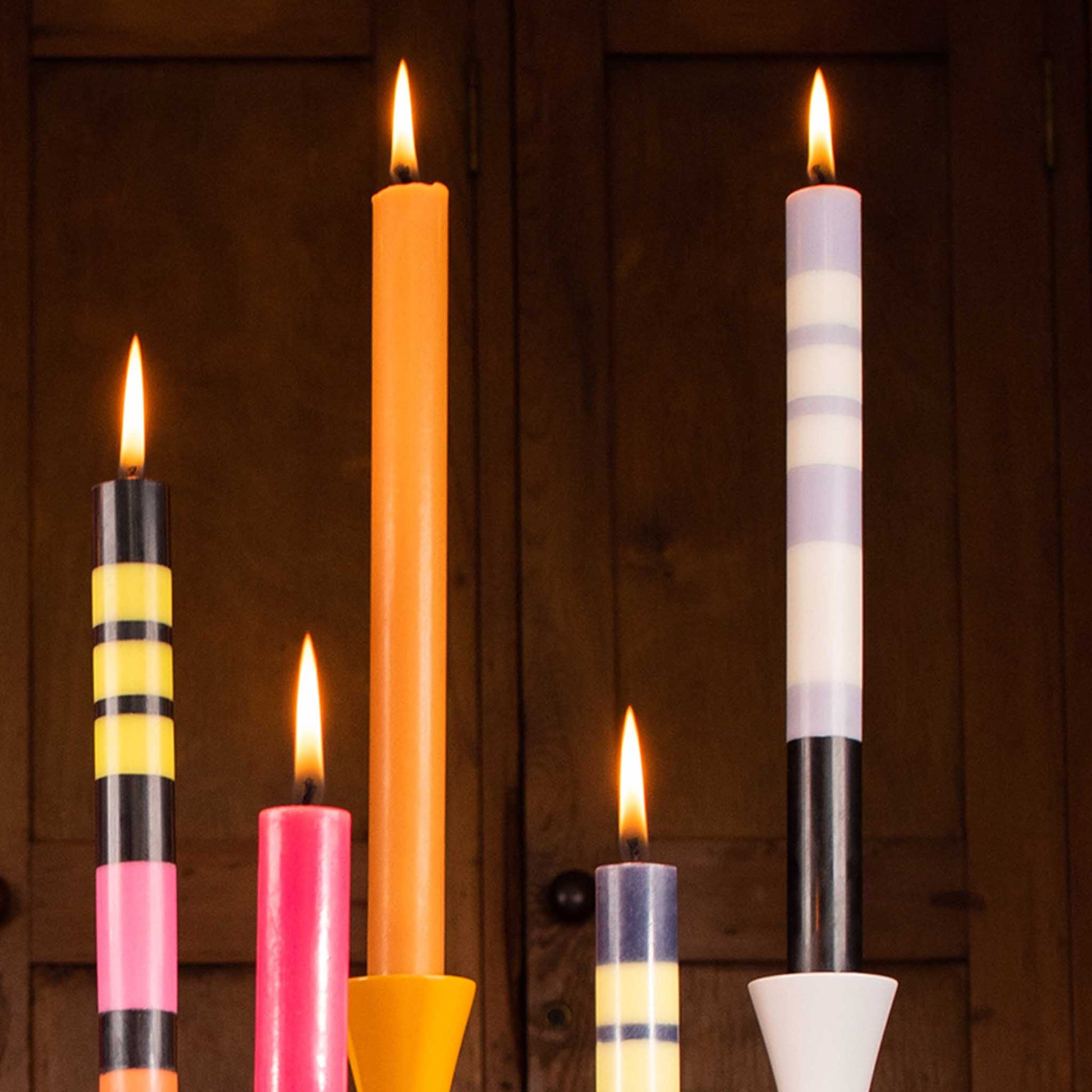 close up shot of lit tall striped candles from the collection