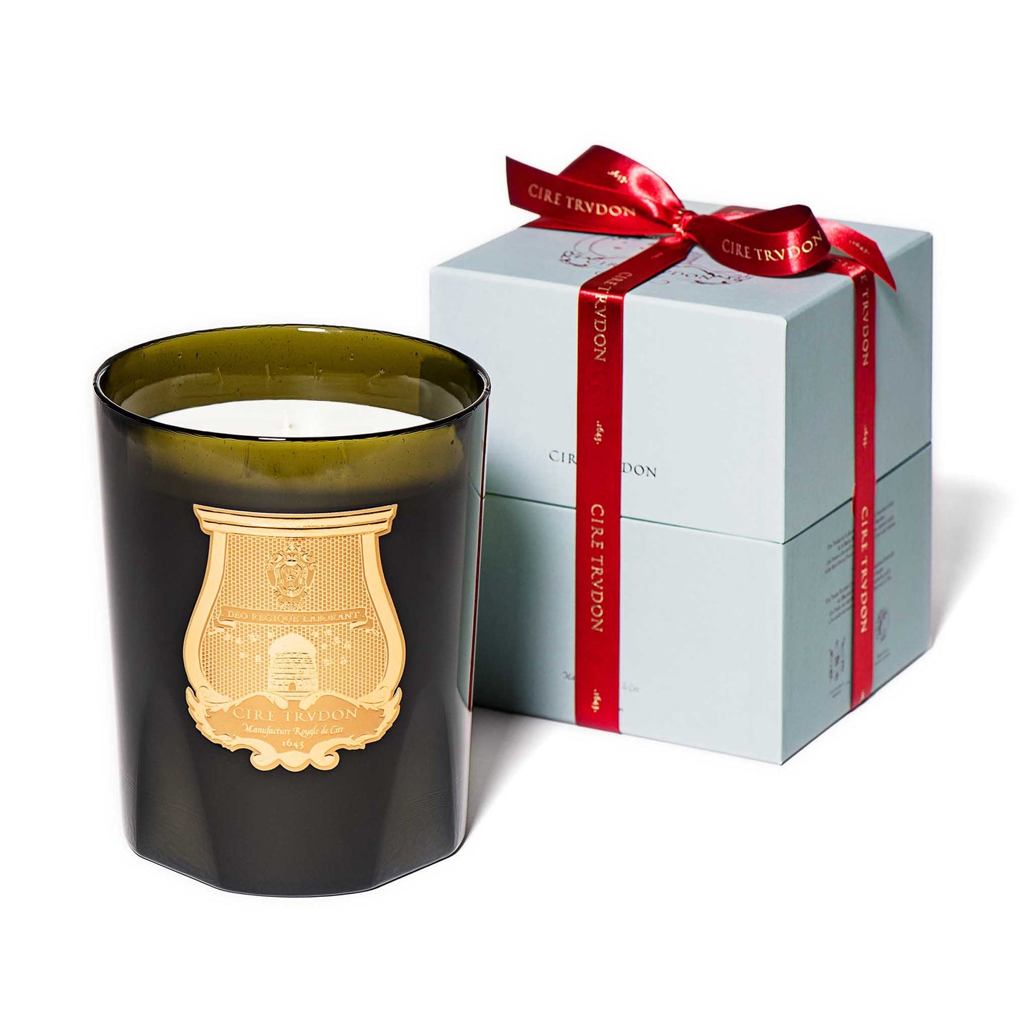 cire trudon candle in a green glass jar with a luxury gold label. this candle comes in a baby blue box with a red ribbon