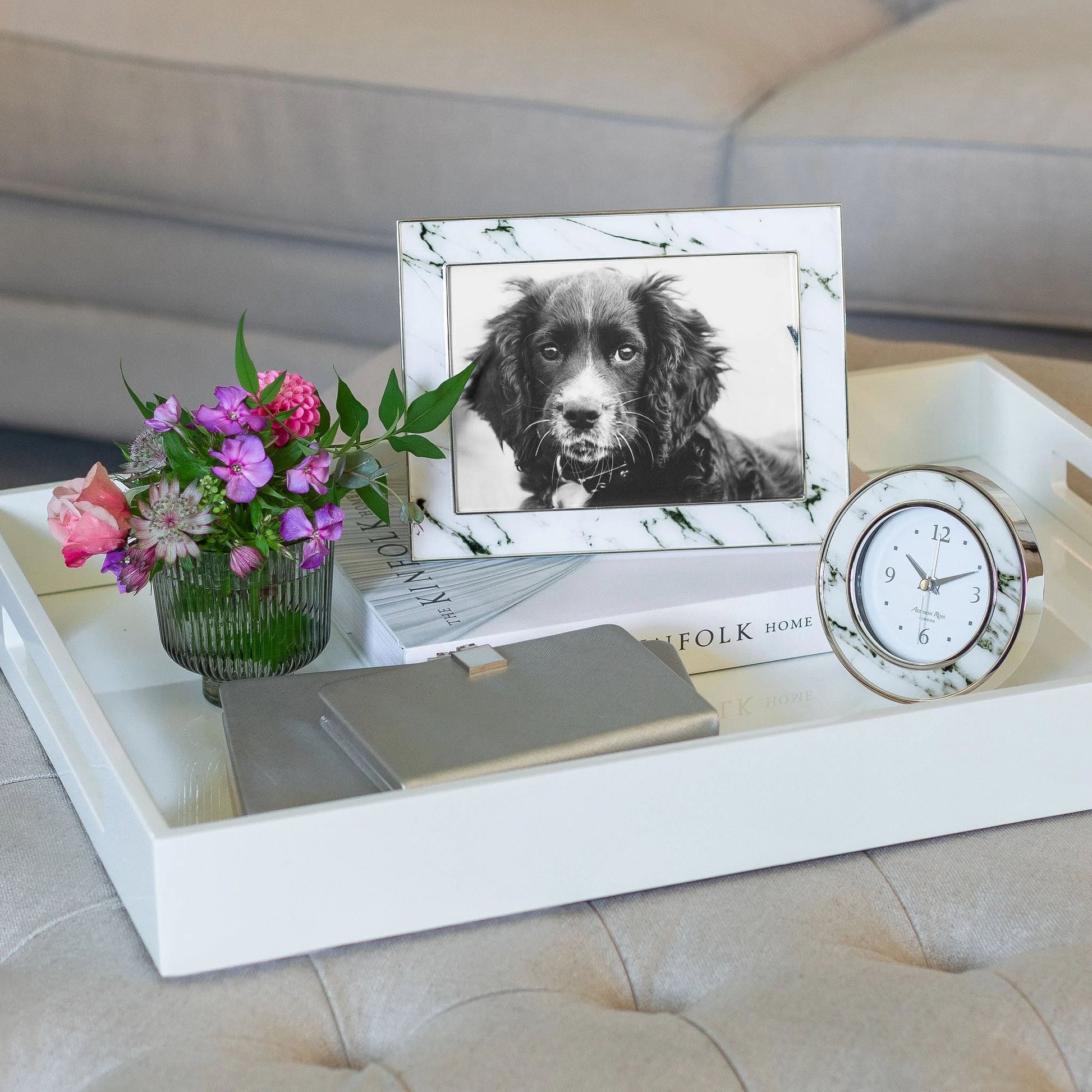 Lifestyle of white marble with black veins and silver photo frame, displayed on white wooden tray in a luxury living room