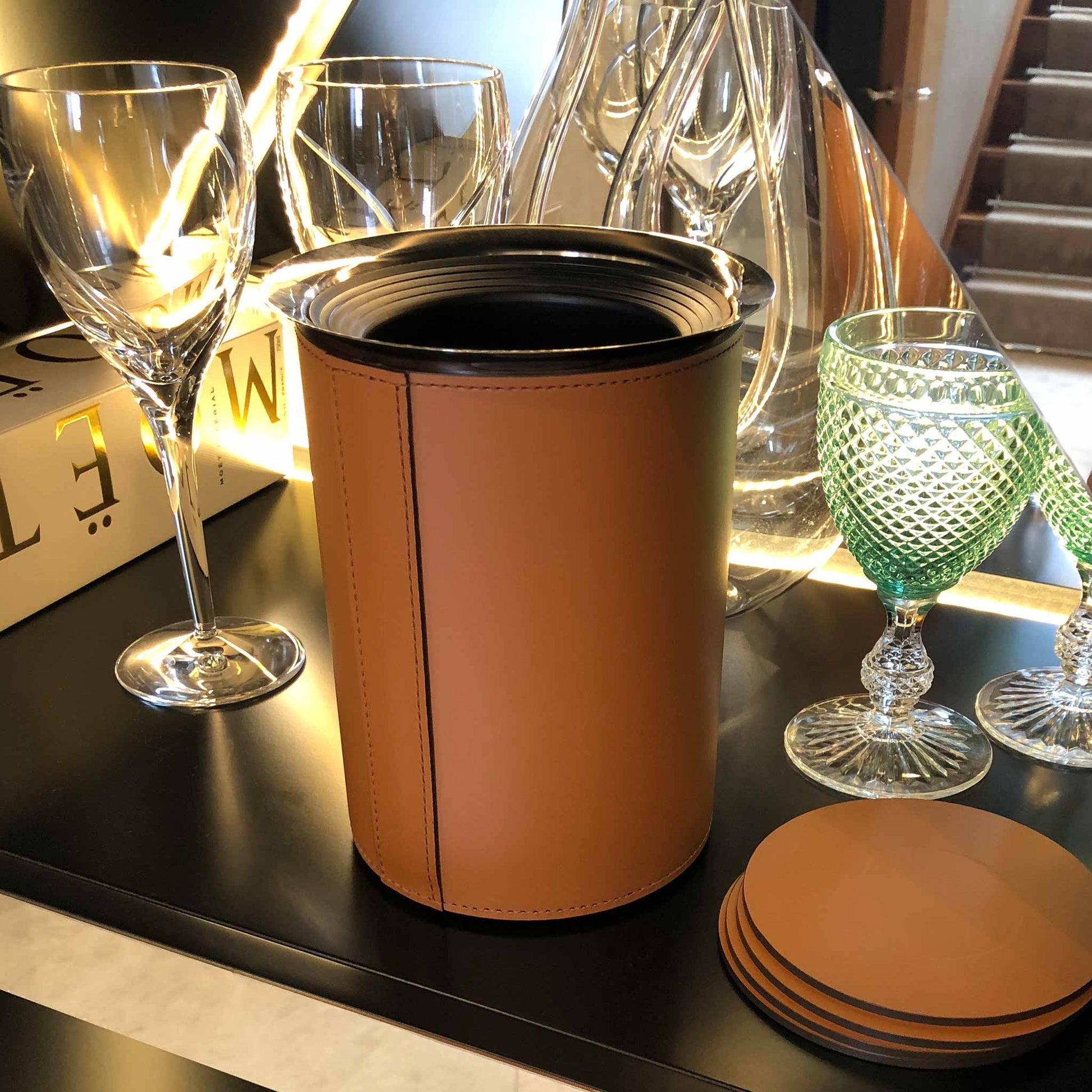 a lifestyle picture showing the leather bottle cooler on a table next to wine glasses