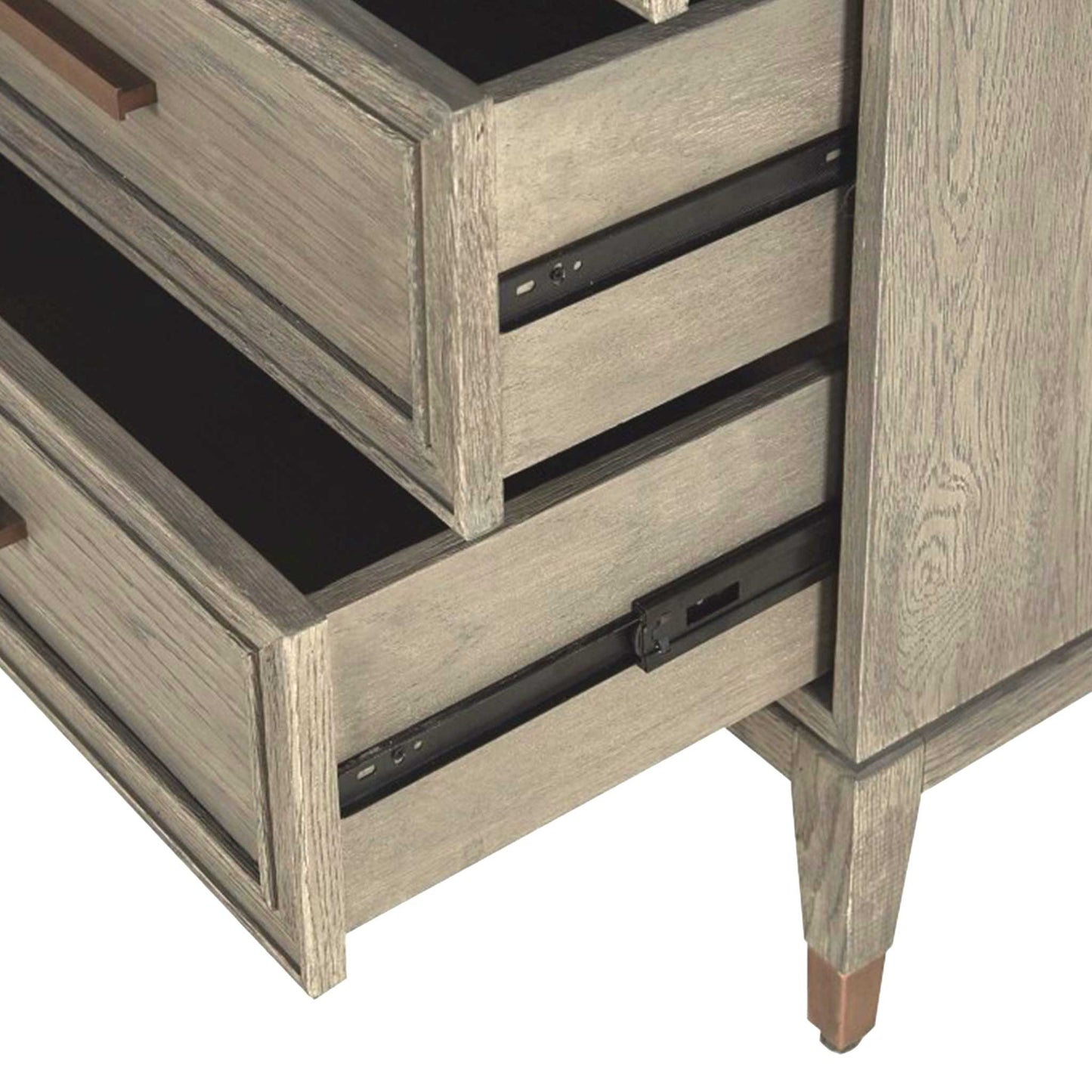 Close up detail of open drawers in light oak chest of three drawers with long brass handles and brass feet