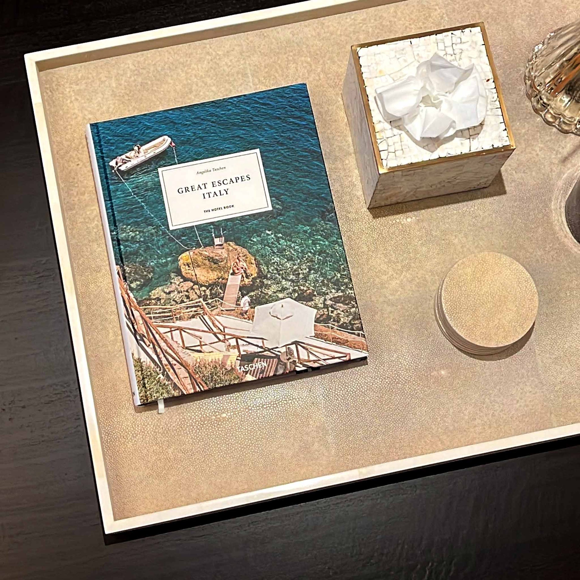 Lifestyle image of natural shagreen rectangular tray with white bone trim displayed with matching coasters and a shell and brass square tissue box